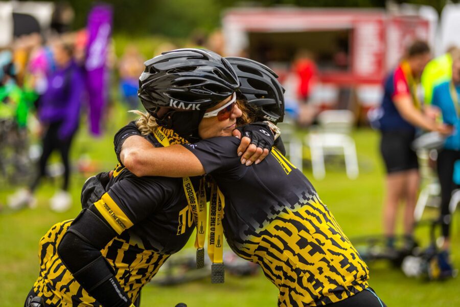 Two riders embracing in Touro jerseys